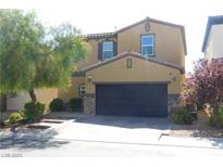 Two-story house with tan exterior, dark garage door, and landscaping at 647 Wounded Star Ave, Las Vegas, NV 89178