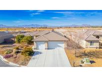 Single-story house with two-car garage, desert landscape, and mountain views at 748 Ishani Ridge Ct, Pahrump, NV 89048